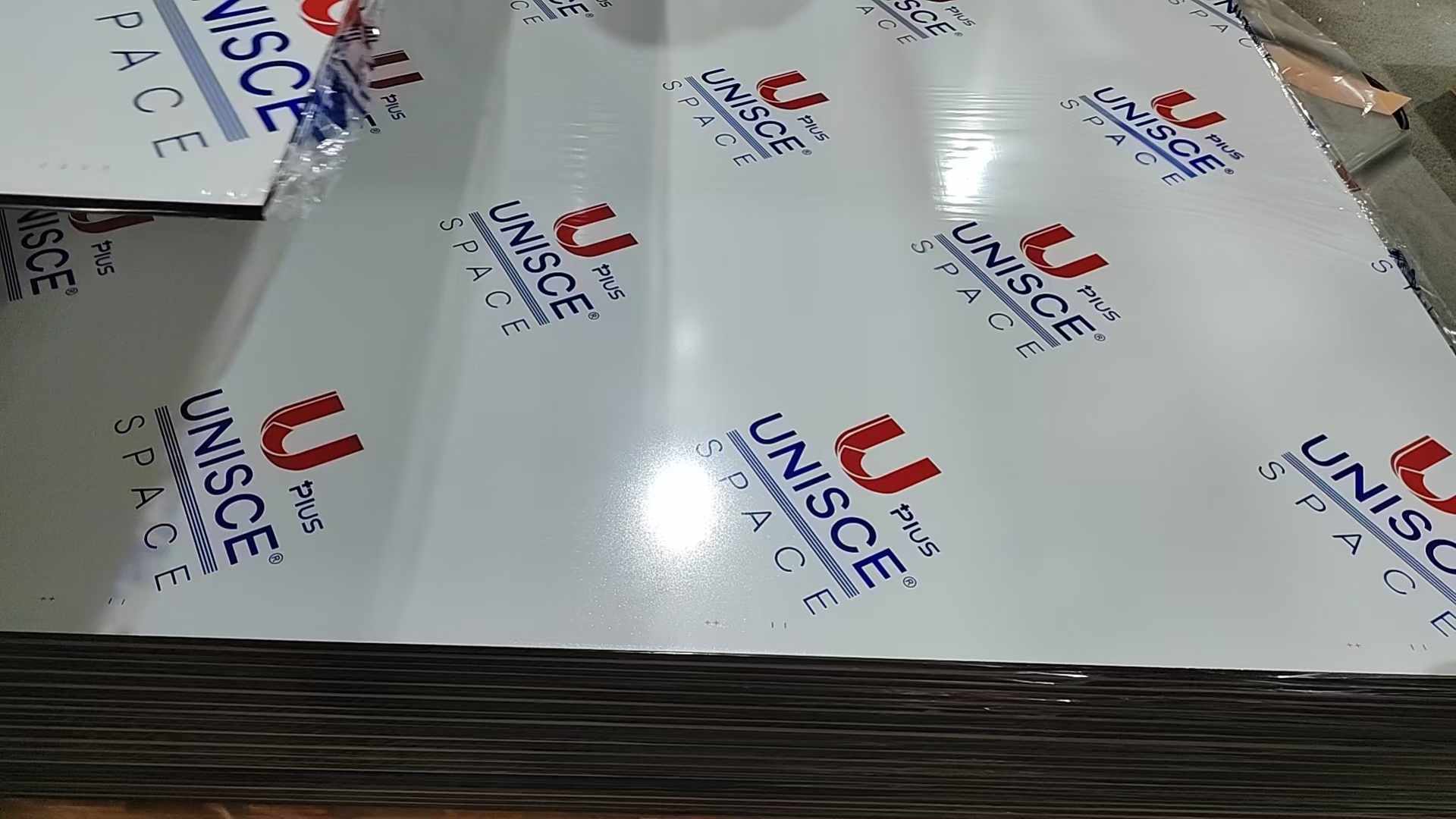 Gloss white compact HPL sheets stacked flat under branded protective film at Cairo House. Solid grade laminate in plain white is a common pick for clinics, kitchens and offices among buyers of Compact HPL in Cairo and New Cairo.