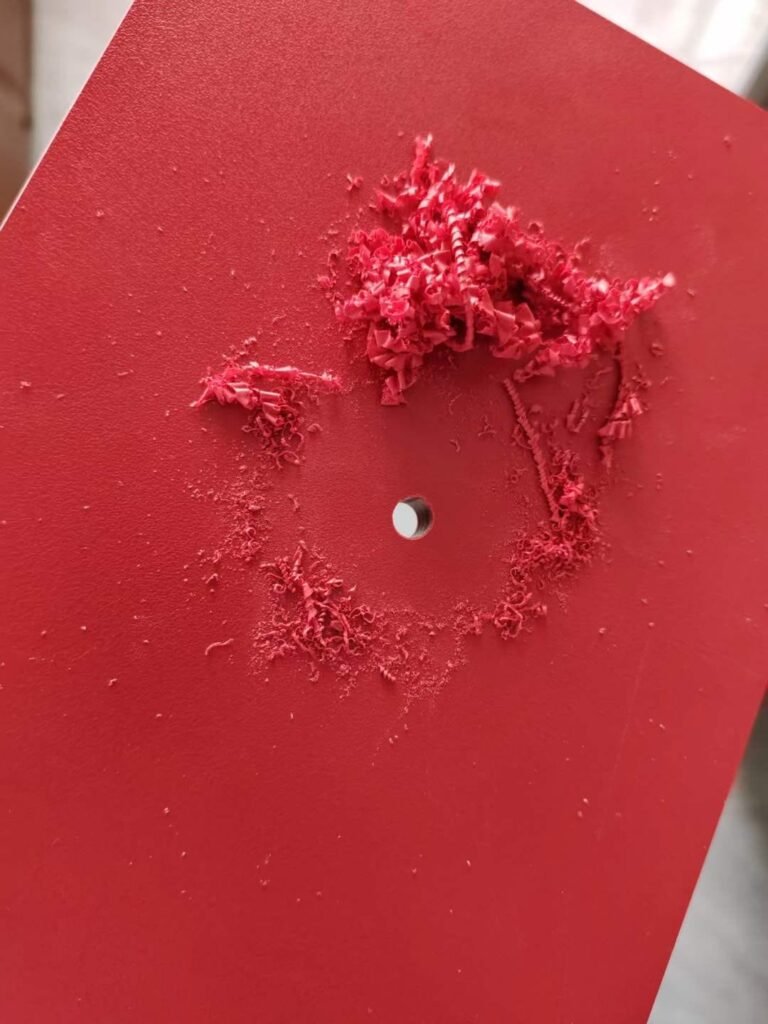 Red compact HPL panel after an impact and drilling test, showing the dense core holding the load at Cairo House in New Nozha, Cairo. Tests like this prove why Compact HPL in Cairo handles screws, fixings and daily wear on site.