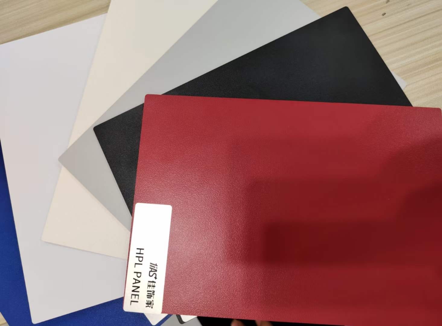 Fanned compact HPL panel samples in white, grey, black and textured red at Cairo House in New Nozha, Cairo. The labelled swatches let clients feel the surface texture before choosing Compact HPL in Cairo finishes for fit out projects.