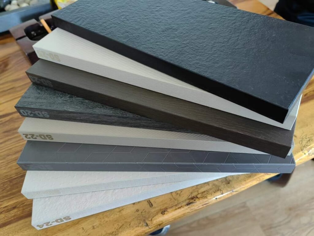 Stacked compact HPL sample panels with stone, slate and geometric textures in black, grey and white at Cairo House in New Nozha, Cairo. The coded range shows the surface textures available on Compact HPL in Cairo for fit out projects.