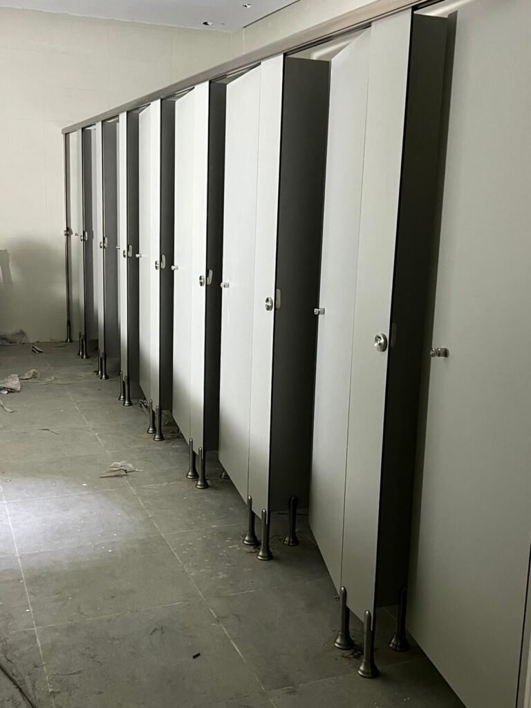 Black and white compact HPL partitions in Cairo running down a long washroom. Cairo House installs UNISCE compact HPL bathroom partitions in contrast colour schemes for offices, malls and factories across Cairo.