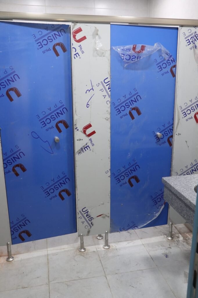 Close up of blue UNISCE film over compact HPL partitions in Cairo, with the stainless knob already fitted. Cairo House leaves the film on compact HPL bathroom partitions until the washroom is handed over in Cairo.