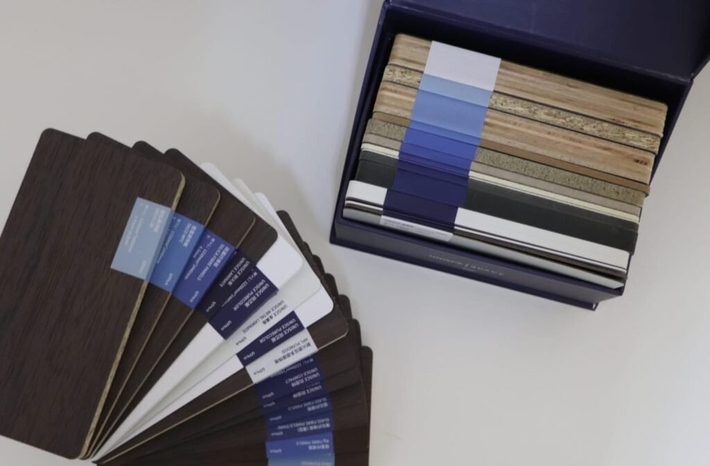 UNISCE colour swatches for compact HPL partitions in Cairo, fanned out across blues, greys and wood grains. Cairo House brings the full sample set to site so clients pick compact HPL bathroom partition colours in the real light.