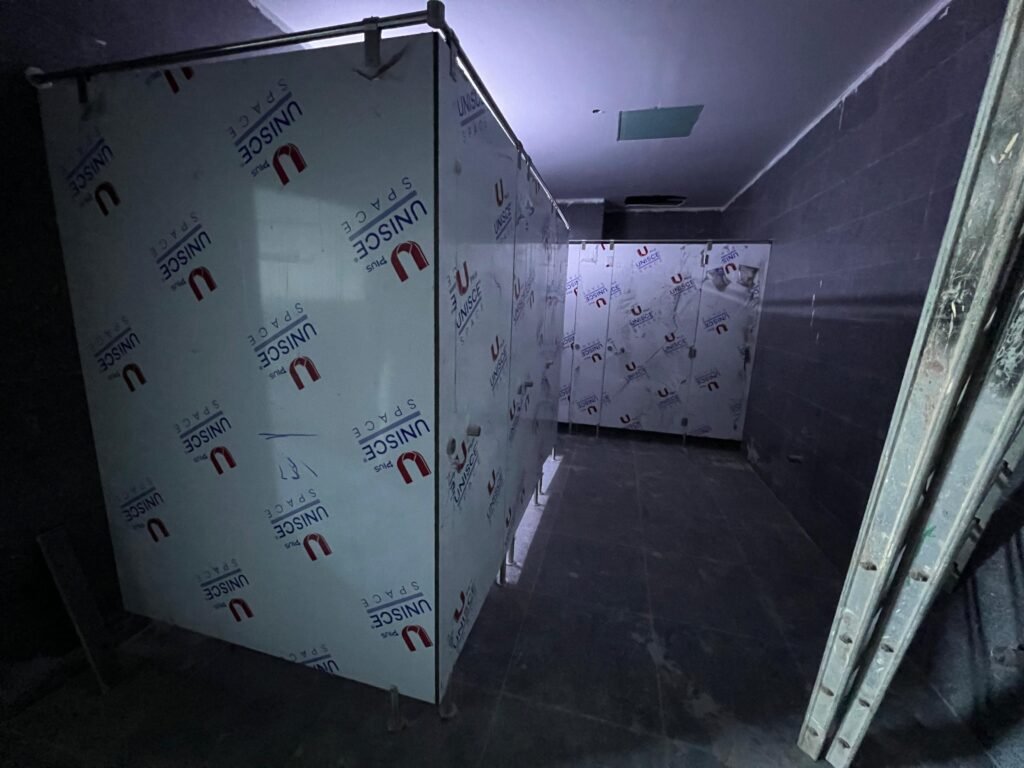 Doorway view into compact HPL partitions in Cairo during installation. Cairo House works compact HPL bathroom partitions around existing marble and tiling rather than asking the contractor to cut back in Cairo.