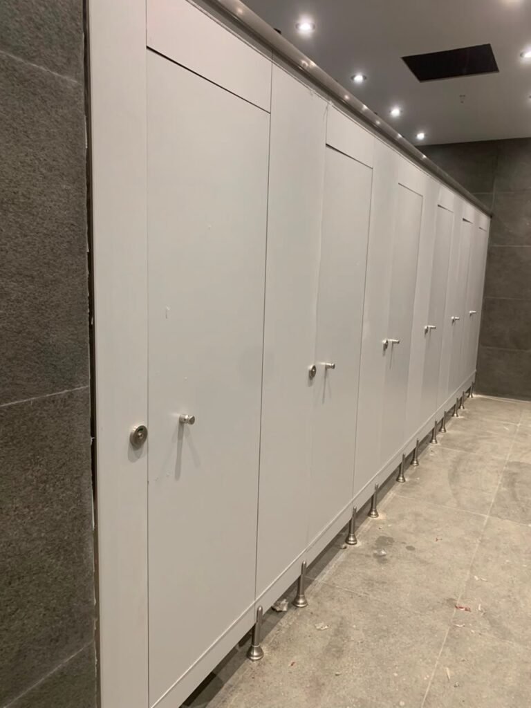 Grey compact HPL partitions in Cairo standing on a polished granite floor during fit out. Cairo House supplies UNISCE compact HPL bathroom partitions in 12mm and 13mm phenolic board for commercial washrooms across Cairo.