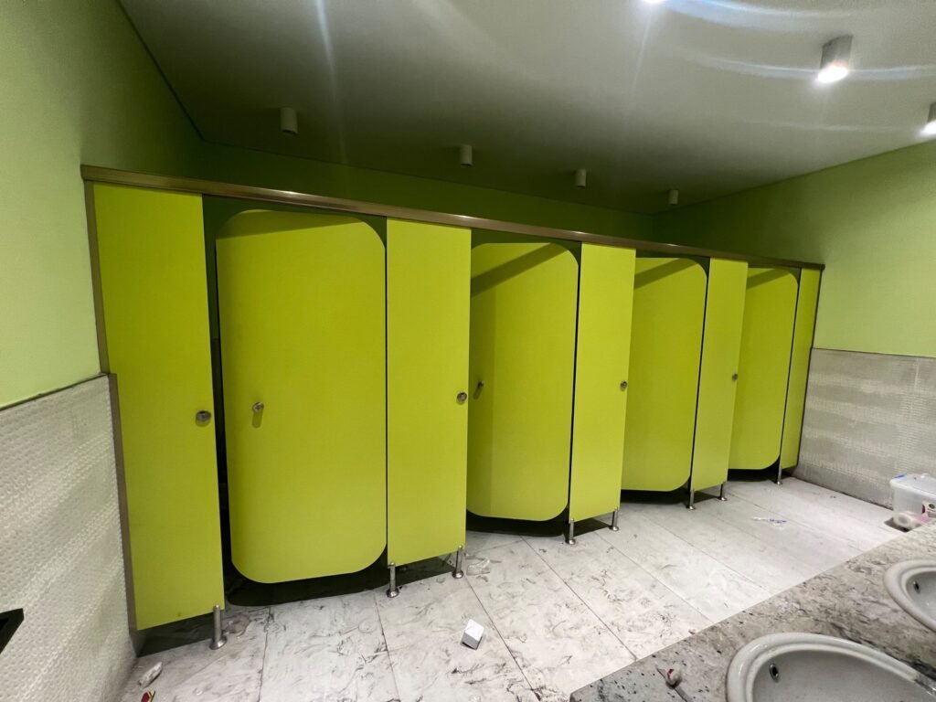 Angled view of lime green compact HPL partitions in Cairo before the floor is finished. Cairo House supplies and installs UNISCE compact HPL bathroom partitions for gyms, clinics and schools throughout Cairo.