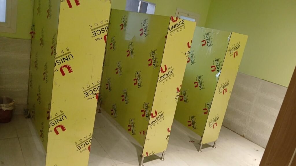 A batch of filmed UNISCE panels for compact HPL partitions in Cairo laid out inside the washroom shell. Cairo House stages compact HPL bathroom partition panels in order of installation to keep Cairo sites moving.