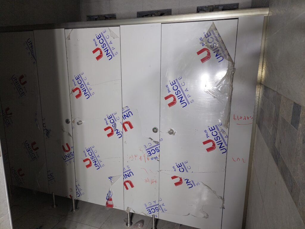 Face detail of a UNISCE panel for compact HPL partitions in Cairo before the film comes off. The board is solid phenolic right through, which is what makes compact HPL bathroom partitions in Cairo last in wet areas.