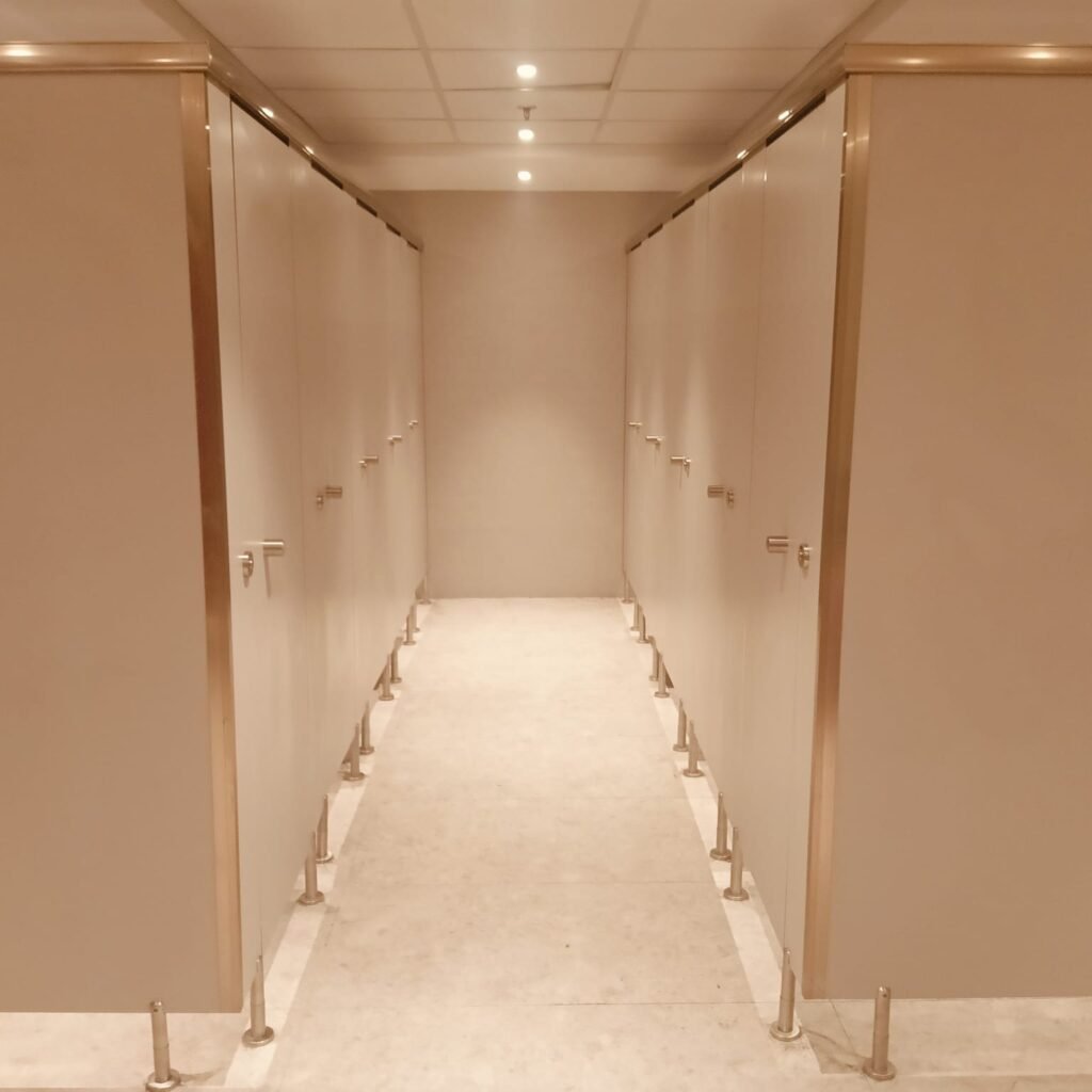 Peach toned compact HPL partitions in Cairo running down a warm lit washroom. Cairo House supplies UNISCE compact HPL bathroom partitions in soft decor tones for hotels and clinics across Cairo and Greater Cairo.
