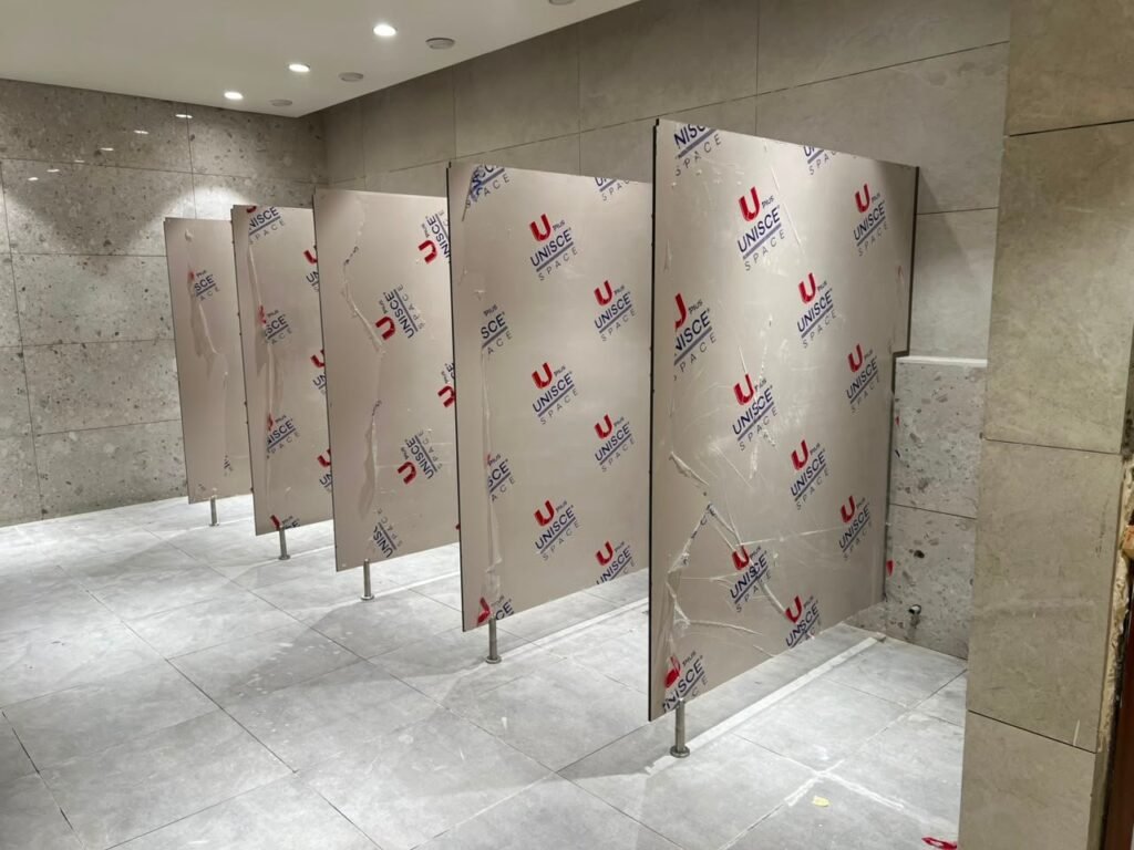 Sand coloured compact HPL partitions in Cairo, filmed and braced while the floor finish is completed. Cairo House returns to set the doors on its compact HPL bathroom partitions once the tiling is done on Cairo sites.