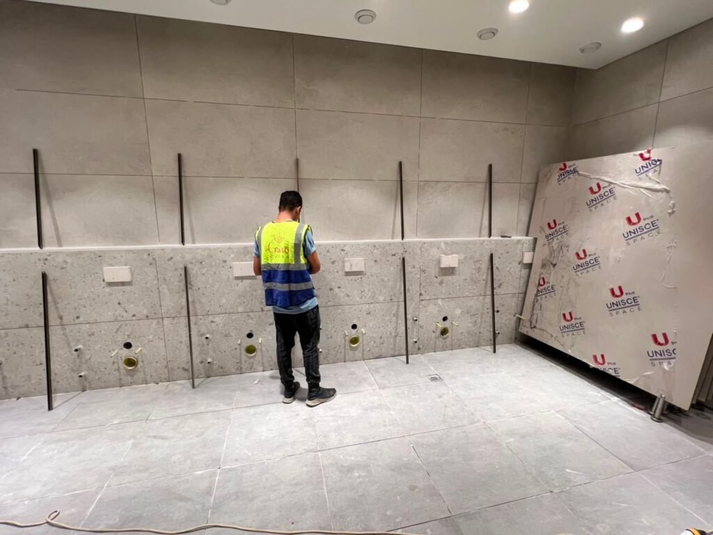 Stainless pilaster posts being set out for compact HPL partitions in Cairo. Getting the frame plumb is what keeps doors on compact HPL bathroom partitions closing true for years in busy Cairo washrooms.