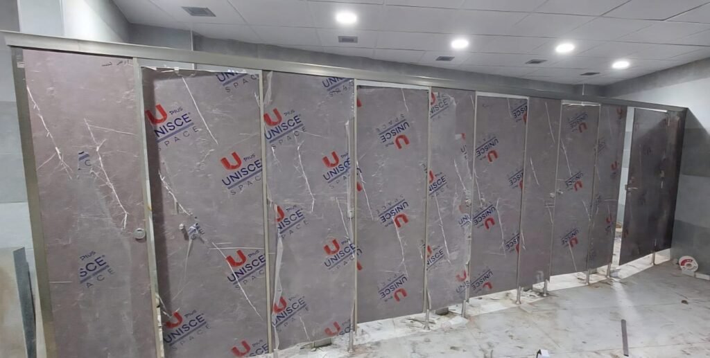A long run of stone look compact HPL partitions in Cairo under ceiling downlights. Cairo House supplies UNISCE compact HPL bathroom partitions in marble and stone decors for Cairo malls, hotels and offices.