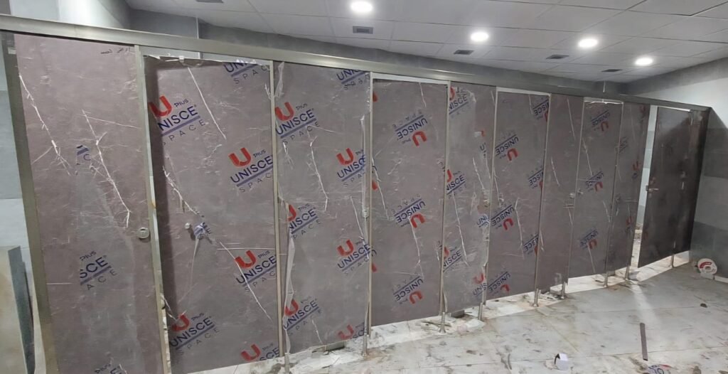 Stone look compact HPL partitions in Cairo photographed down the washroom before final clean. Cairo House installs compact HPL bathroom partitions to the setting out drawing on Cairo commercial fit outs.
