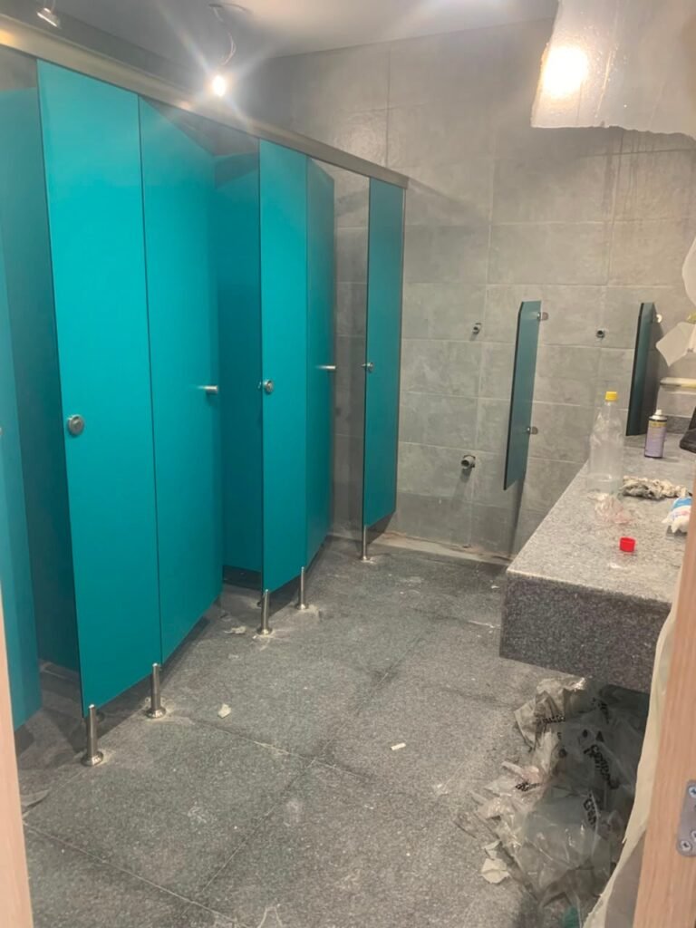 Teal compact HPL partitions in Cairo beside a marble vanity still under construction. Cairo House phases UNISCE compact HPL bathroom partition installation around the main contractor programme on Cairo sites.