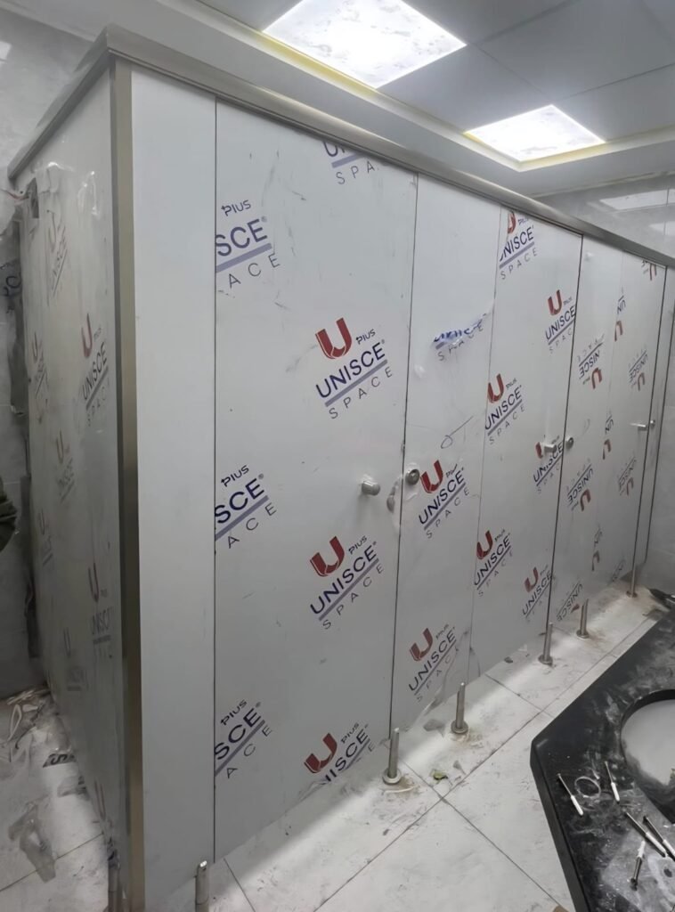 UNISCE Space branded film across compact HPL partitions in Cairo during fit out. The film protects the phenolic face while trades finish around the compact HPL bathroom partitions on Cairo commercial sites.