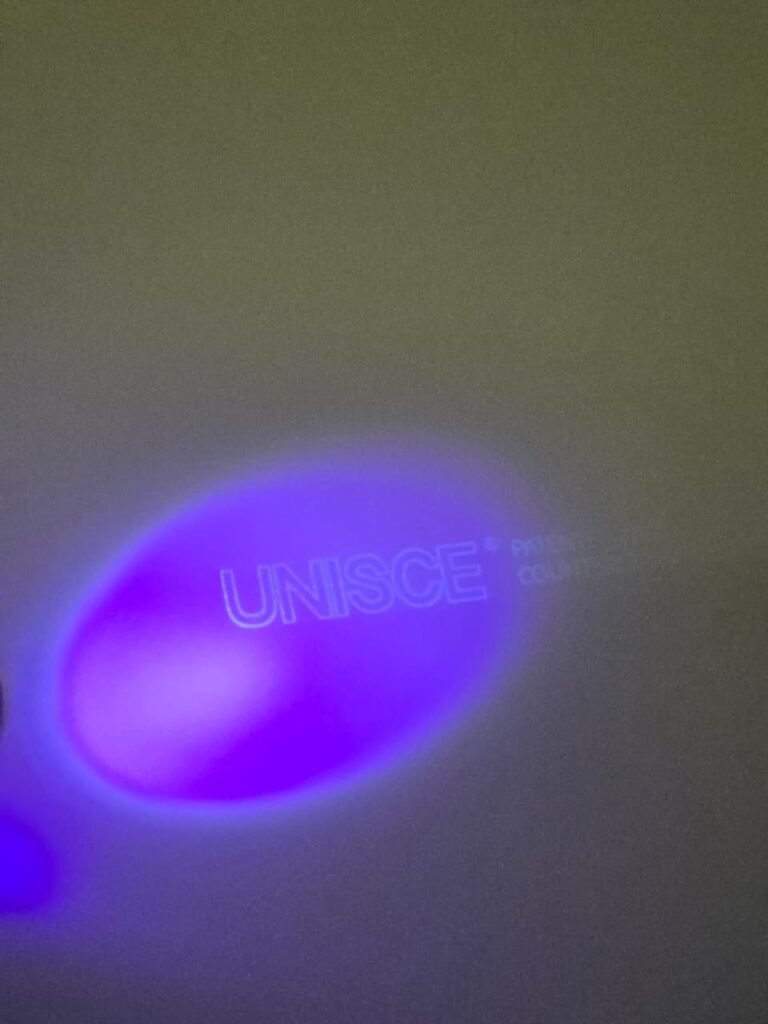 The UNISCE hologram showing under UV light on a panel for compact HPL partitions in Cairo. Cairo House checks every board on arrival so clients get genuine UNISCE compact HPL bathroom partitions in Cairo, not a copy.