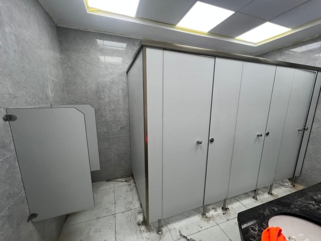 White compact HPL partitions in Cairo with the doors swung open after hanging. Cairo House checks every door on its compact HPL bathroom partitions for swing, gap and lock alignment before leaving a Cairo site.