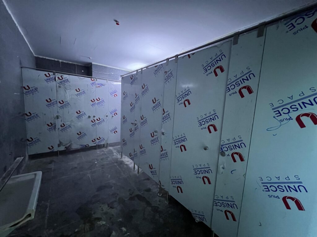 Wide view of compact HPL partitions in Cairo with every panel still filmed. Cairo House supplies, delivers and installs UNISCE compact HPL bathroom partitions as one package on commercial jobs across Cairo.
