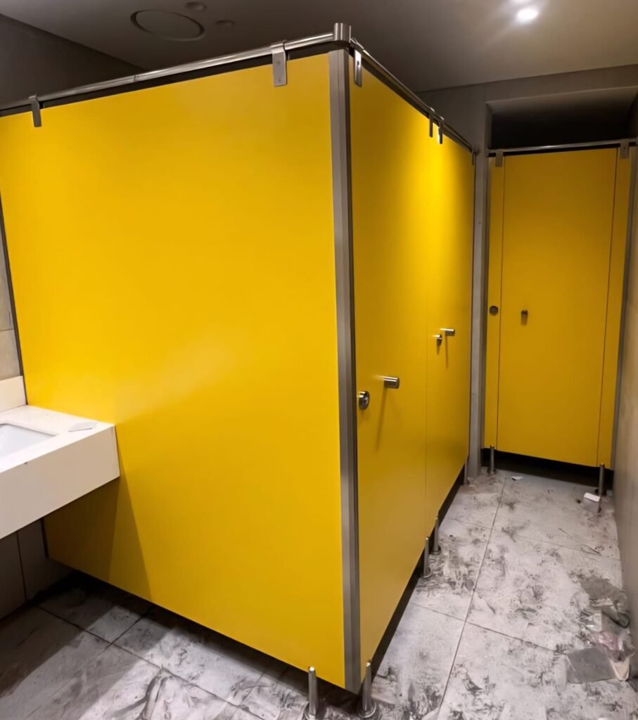 Yellow and grey compact HPL partitions in Cairo fitted in a washroom under construction. Cairo House mixes UNISCE colours across a compact HPL bathroom partition run when the design calls for accent cubicles in Cairo.