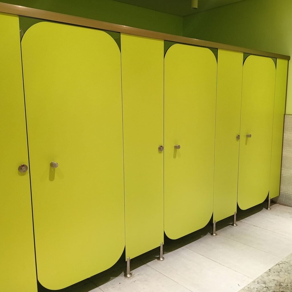 Yellow green compact HPL partitions in Cairo with slim stainless indicator locks. Solid colour compact HPL bathroom partitions like these are common in Cairo gyms and schools where the washroom needs to read bright and clean.