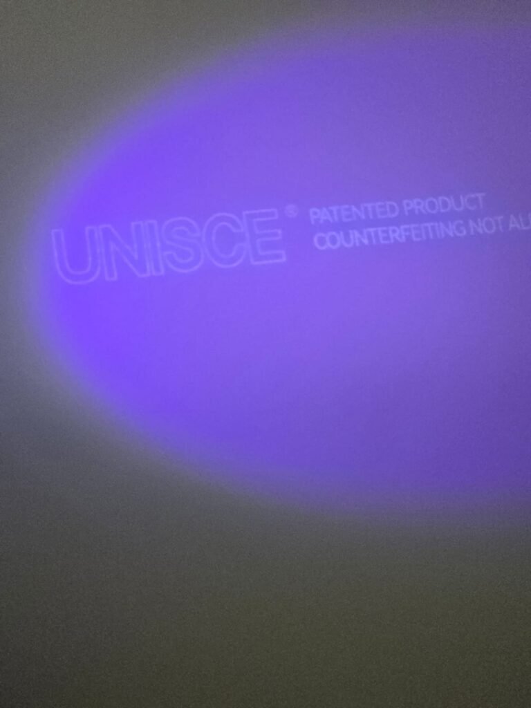 UNISCE anti-counterfeit mark glowing under UV on an HPL partition panel