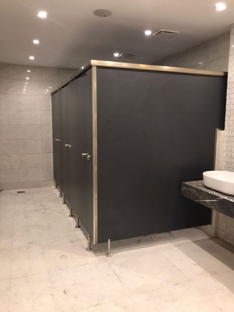 Dark grey compact HPL cubicles beside a basin by Cairo House
